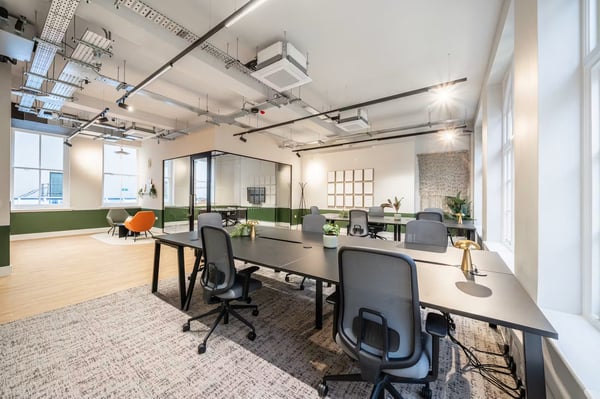 Contemporary desks and ergonomic seating sit alongside a glass-fronted meeting room, keeping the team connected throughout the day.